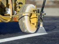 Road construction machine putting white line on asphalt 